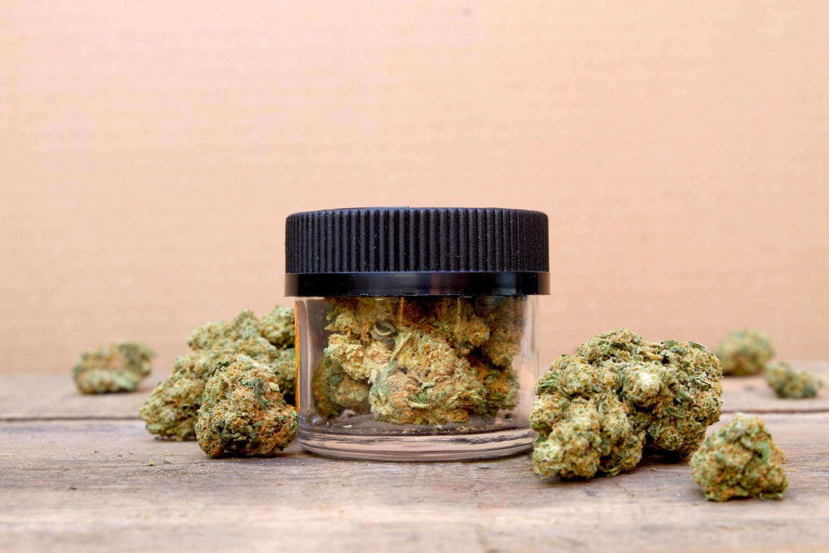 Jar of cannabis buds on a wooden table