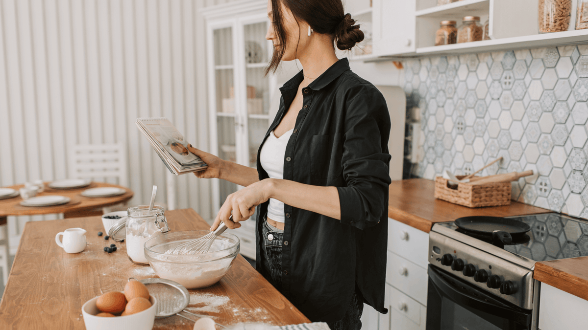 Woman whisking batter in a kitchen while reading a recipe