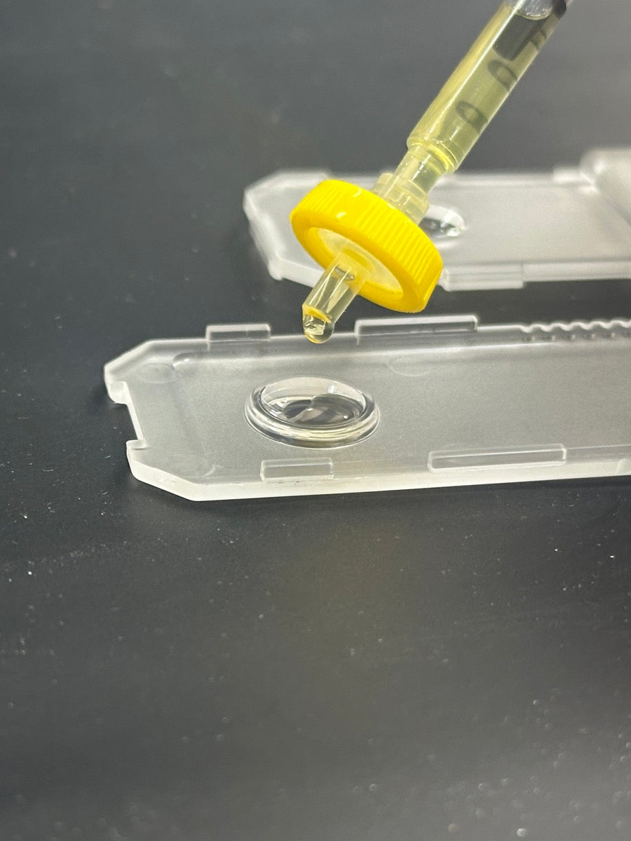 Syringe placing a drop of sample into the tCheck testing tray